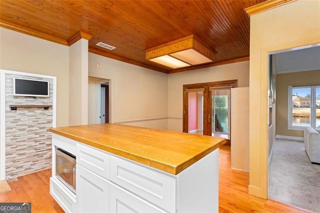 kitchen featuring white cabinetry, butcher block counters, crown molding, wooden ceiling, and light wood-type flooring