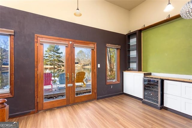 entryway with bar area, wine cooler, light wood-type flooring, and french doors