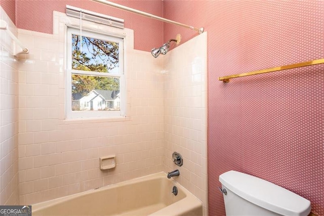 bathroom featuring tiled shower / bath combo and toilet