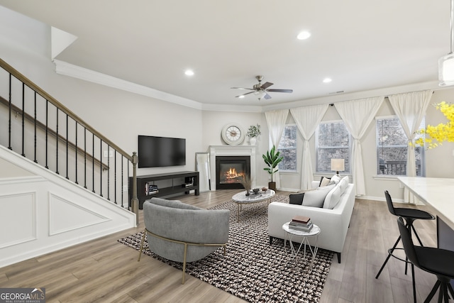 living room featuring crown molding, ceiling fan, and wood-type flooring