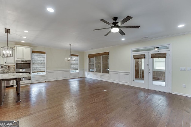 unfurnished living room with ceiling fan with notable chandelier, crown molding, wood finished floors, and recessed lighting