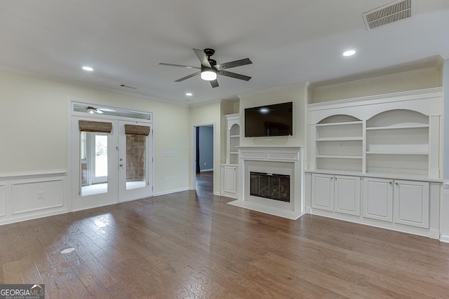 unfurnished living room with visible vents, a glass covered fireplace, a ceiling fan, and wood finished floors