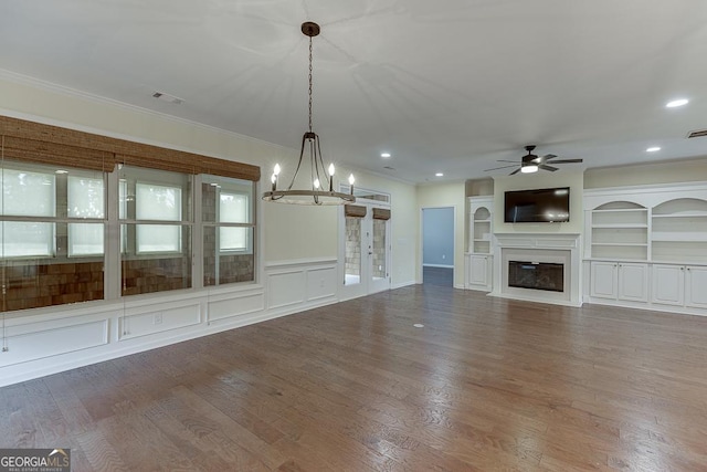 unfurnished living room with built in features, wood-type flooring, ornamental molding, and ceiling fan