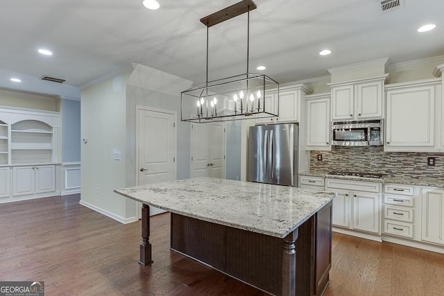 kitchen with hanging light fixtures, stainless steel appliances, white cabinets, and a kitchen island