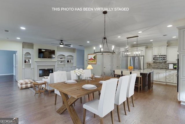 dining area featuring a glass covered fireplace, visible vents, recessed lighting, and wood finished floors