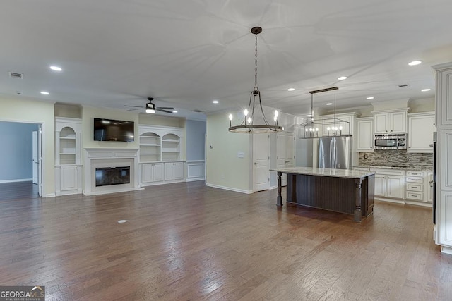 kitchen with visible vents, a glass covered fireplace, light stone counters, a kitchen breakfast bar, and stainless steel appliances