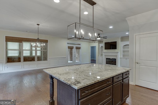 kitchen with hanging light fixtures, dark brown cabinets, a center island, and wood-type flooring