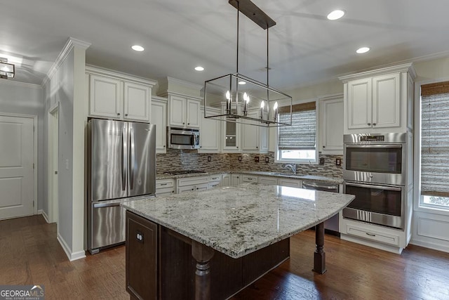 kitchen with stainless steel appliances, a sink, ornamental molding, backsplash, and dark wood-style floors