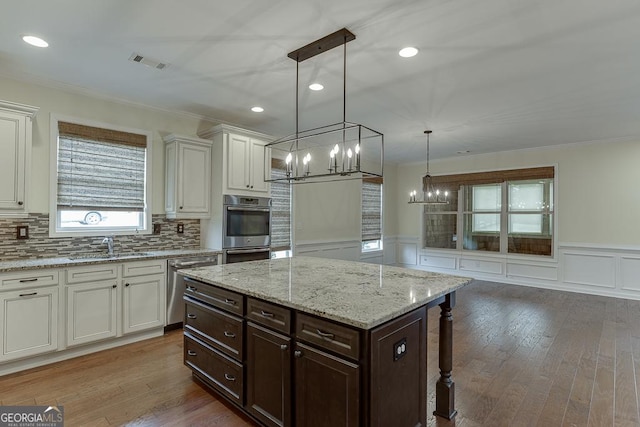 kitchen featuring wood finished floors, appliances with stainless steel finishes, a sink, and visible vents