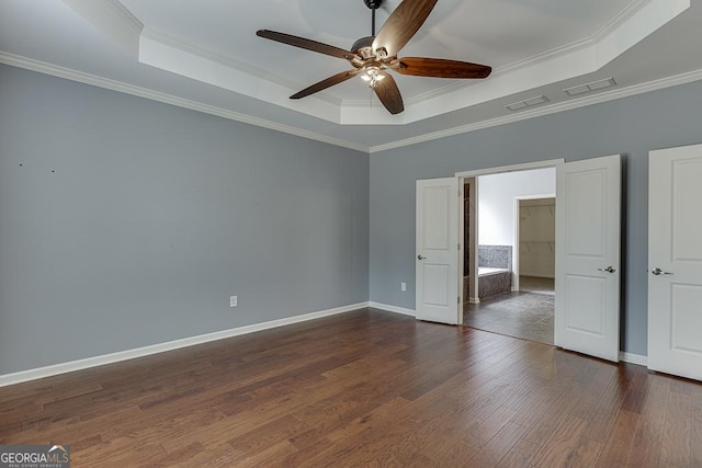 unfurnished bedroom featuring a tray ceiling, dark wood-type flooring, and ornamental molding