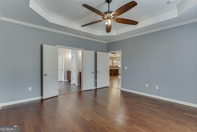 unfurnished bedroom with dark wood-type flooring, ceiling fan, ornamental molding, and a tray ceiling