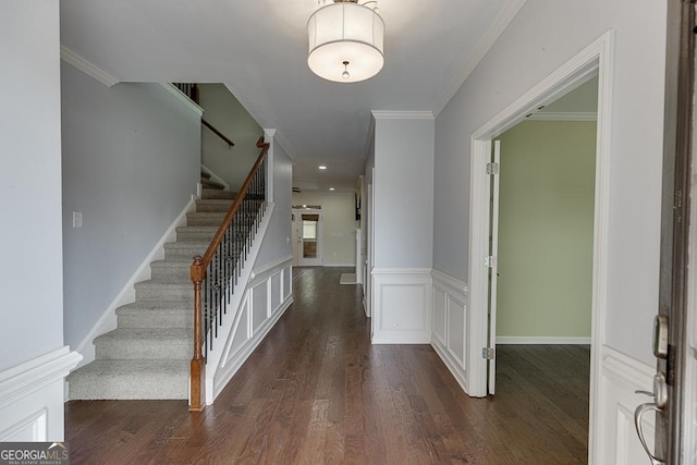 foyer entrance with a wainscoted wall, crown molding, stairway, and wood finished floors