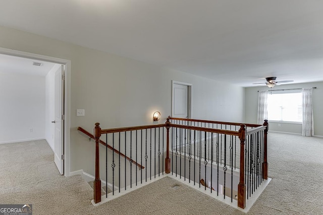 hall with baseboards, carpet flooring, visible vents, and an upstairs landing