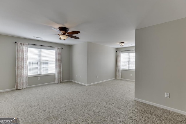 carpeted spare room featuring visible vents, ceiling fan, and baseboards