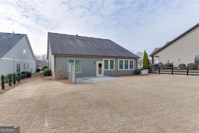 back of property with a patio area, a shingled roof, and fence