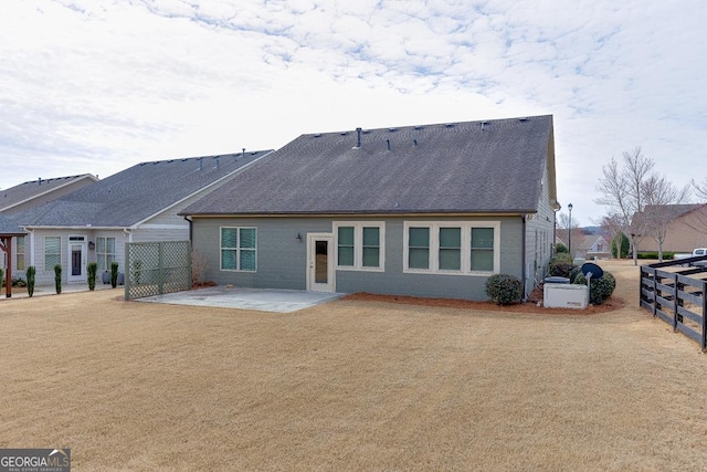 back of house with a patio area, a shingled roof, fence, and brick siding