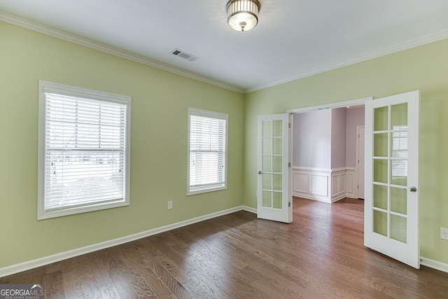 empty room featuring visible vents, baseboards, dark wood-style floors, ornamental molding, and french doors