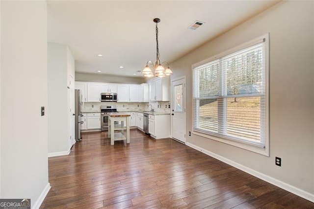 kitchen with dark hardwood / wood-style floors, pendant lighting, white cabinetry, backsplash, and stainless steel appliances