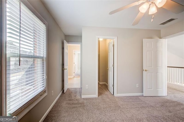 unfurnished bedroom featuring ceiling fan, a walk in closet, light colored carpet, and a closet