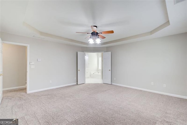 carpeted empty room with a tray ceiling and ceiling fan