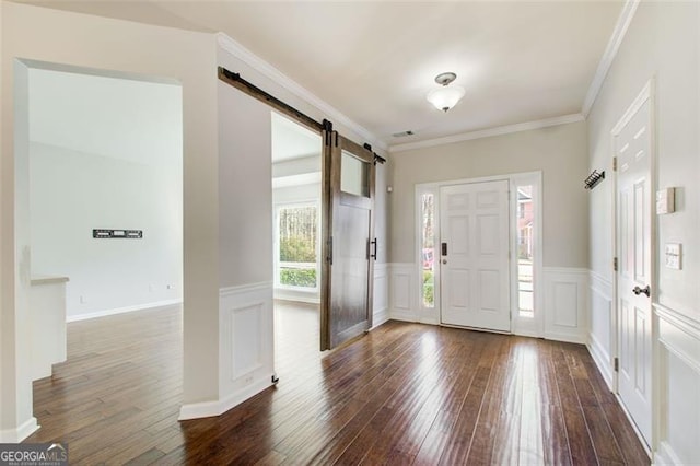 entrance foyer with dark hardwood / wood-style floors, a barn door, and crown molding