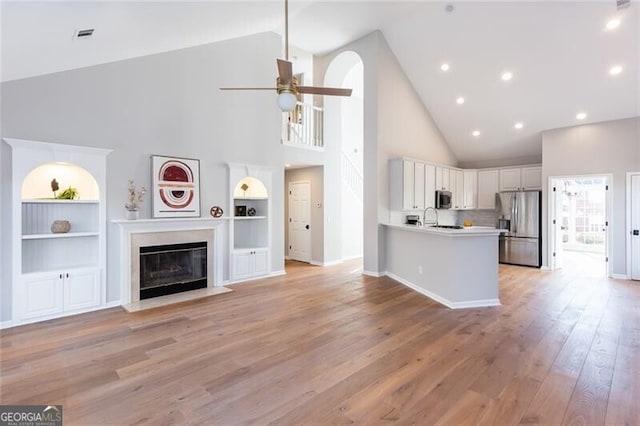 kitchen featuring light hardwood / wood-style flooring, appliances with stainless steel finishes, kitchen peninsula, ceiling fan, and white cabinets