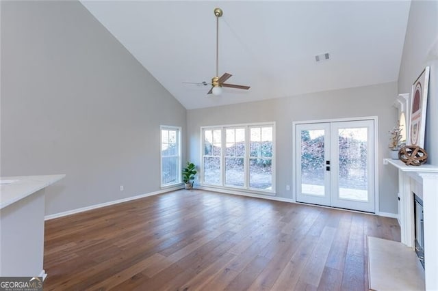 unfurnished living room featuring hardwood / wood-style flooring, ceiling fan, high vaulted ceiling, and french doors