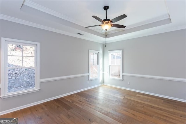 unfurnished room with hardwood / wood-style flooring, ornamental molding, ceiling fan, and a tray ceiling