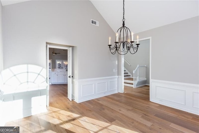 unfurnished dining area featuring light hardwood / wood-style flooring, a chandelier, and vaulted ceiling