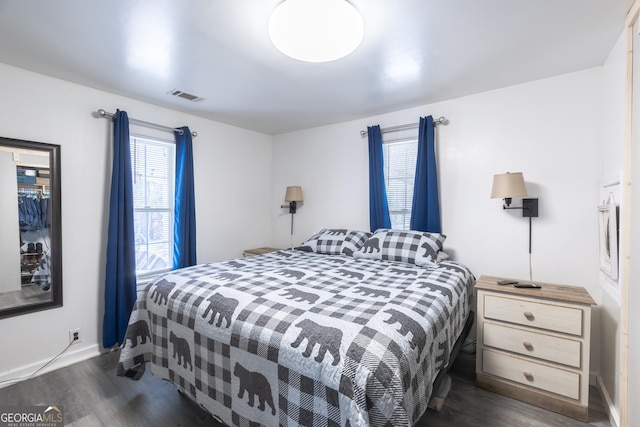 bedroom with multiple windows and dark hardwood / wood-style flooring