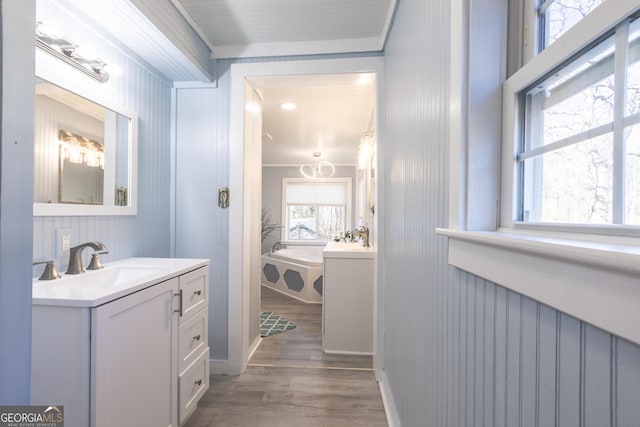 bathroom with hardwood / wood-style flooring, ornamental molding, a tub to relax in, and vanity