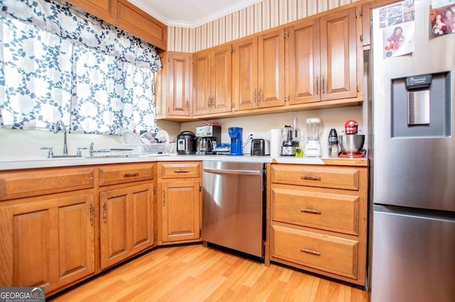 kitchen featuring crown molding, stainless steel appliances, sink, and light wood-type flooring