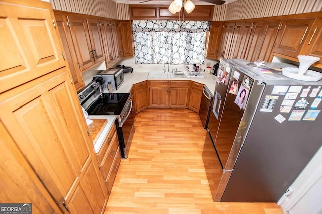 kitchen featuring appliances with stainless steel finishes, sink, ceiling fan, and light hardwood / wood-style flooring