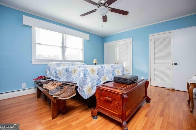 bedroom featuring multiple closets, ornamental molding, light hardwood / wood-style floors, and a baseboard heating unit