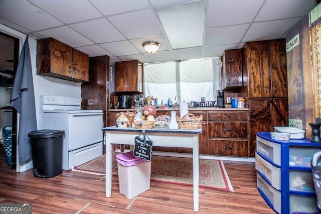 kitchen with hardwood / wood-style floors, a kitchen bar, dark brown cabinetry, white range with electric cooktop, and a drop ceiling