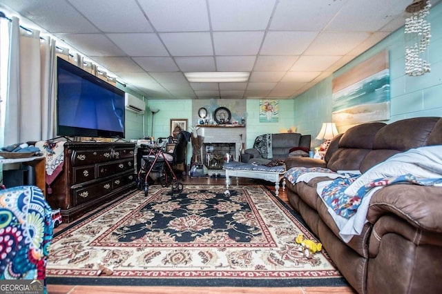 living room with an AC wall unit and a paneled ceiling