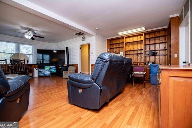 living room with ceiling fan, ornamental molding, and light hardwood / wood-style flooring