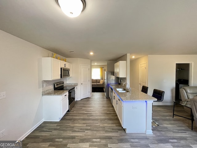 kitchen featuring sink, white cabinetry, a kitchen breakfast bar, kitchen peninsula, and stainless steel appliances