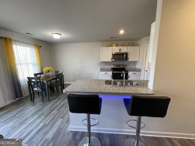 kitchen with sink, a breakfast bar area, range with electric cooktop, white cabinets, and kitchen peninsula