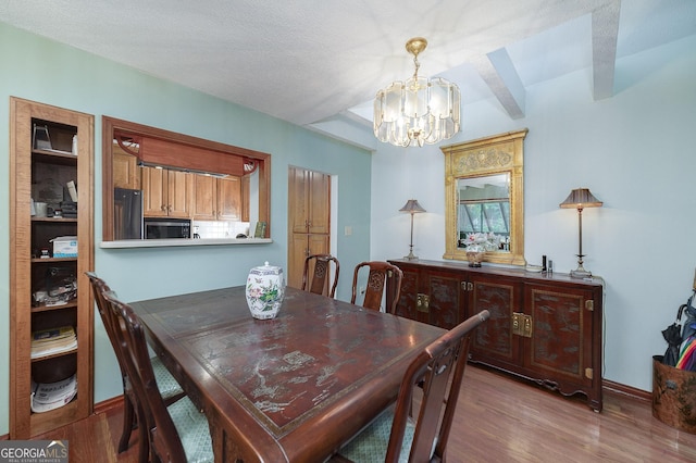 dining room with an inviting chandelier, wood-type flooring, and a textured ceiling