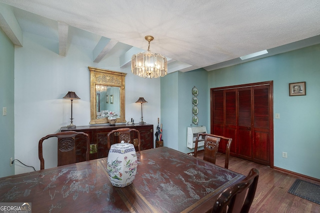 dining space with wood-type flooring, a textured ceiling, and a chandelier