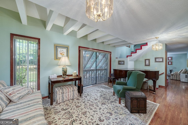 living room featuring hardwood / wood-style flooring, beam ceiling, a textured ceiling, and a notable chandelier