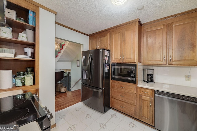 kitchen with crown molding, appliances with stainless steel finishes, backsplash, and a textured ceiling