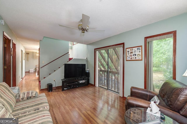 living room featuring ceiling fan, plenty of natural light, light hardwood / wood-style floors, and a textured ceiling