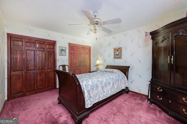 carpeted bedroom featuring multiple closets, a textured ceiling, and ceiling fan