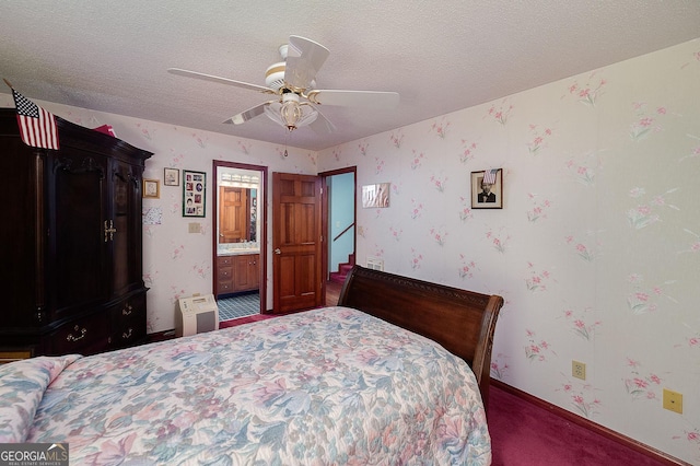 bedroom with ceiling fan, ensuite bathroom, a textured ceiling, and dark colored carpet