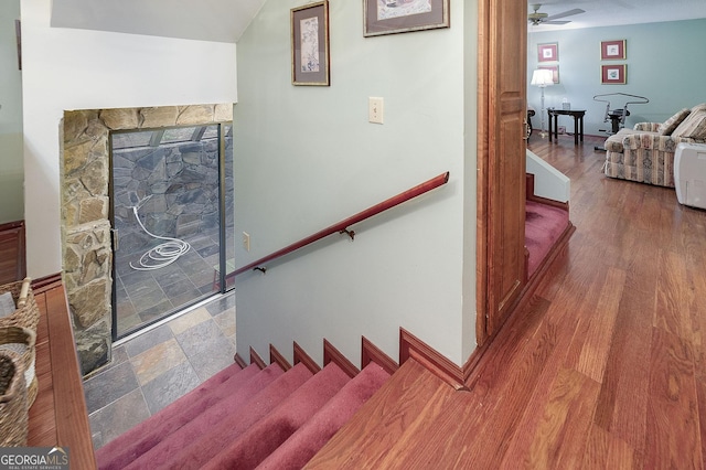 staircase featuring ceiling fan, hardwood / wood-style floors, and a fireplace