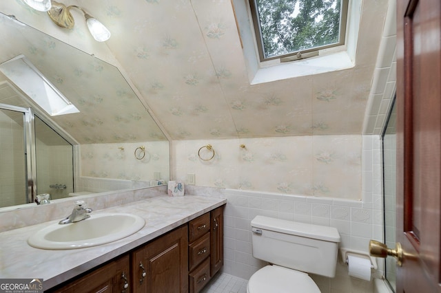 bathroom with lofted ceiling with skylight, tile walls, vanity, walk in shower, and toilet