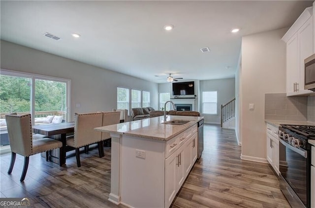 kitchen with appliances with stainless steel finishes, sink, white cabinets, backsplash, and light stone counters