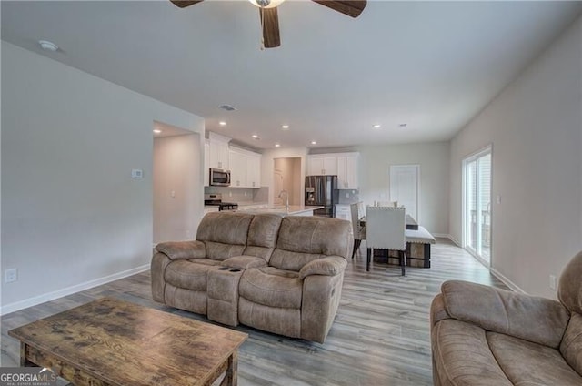 living room with ceiling fan, sink, and light hardwood / wood-style floors